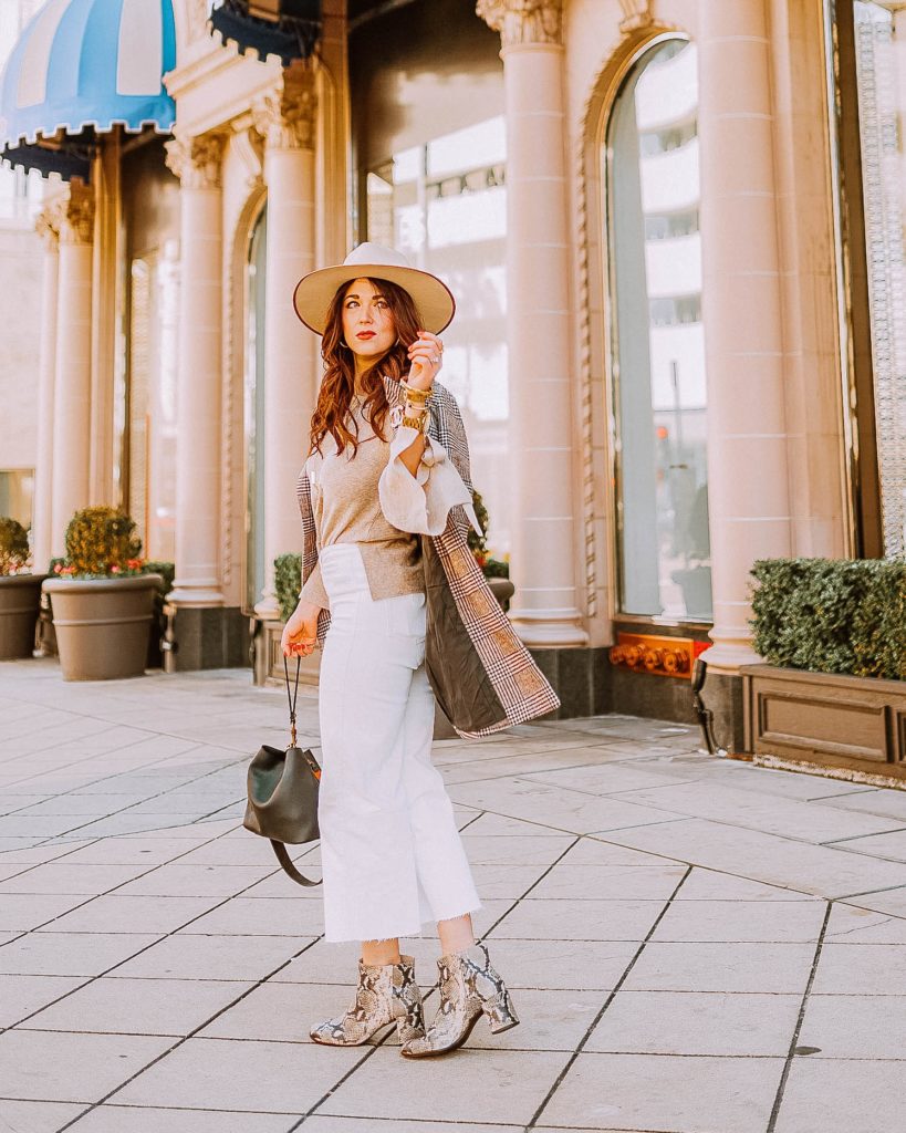 Girl in a hat standing on sidewalk in winter neutrals