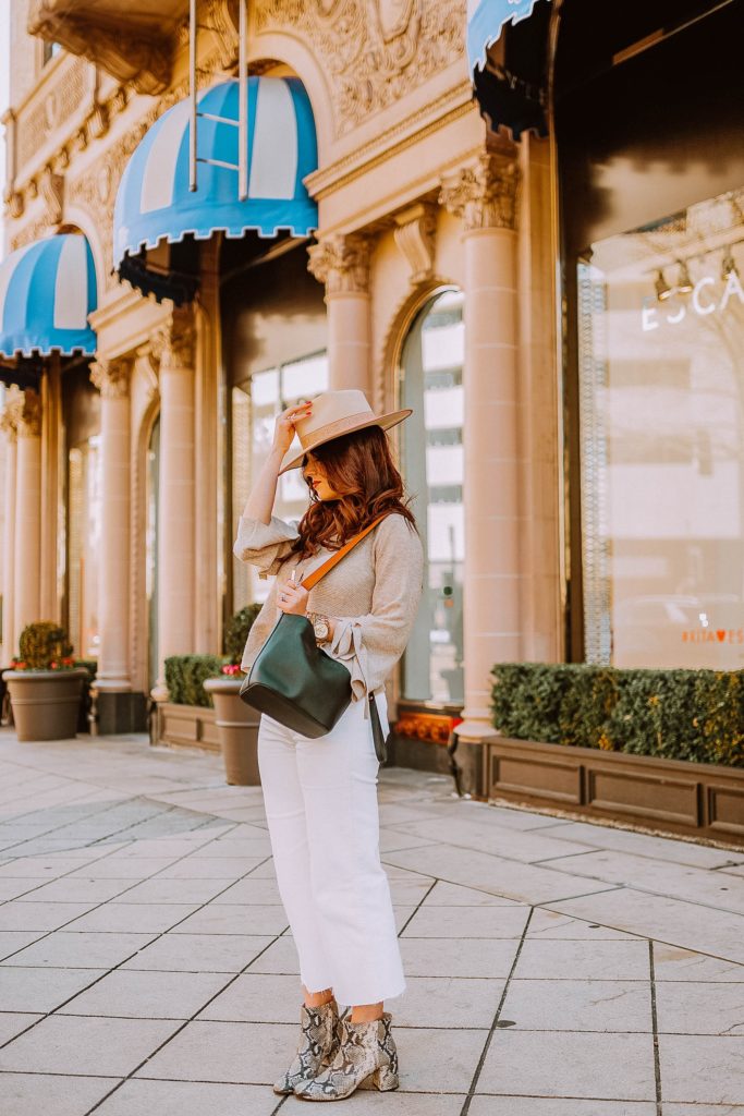 Girl in a hat standing on sidewalk in winter neutrals