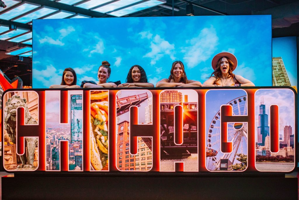 Girls posing behind a Chicago sign at the Chicago Skydeck Museum