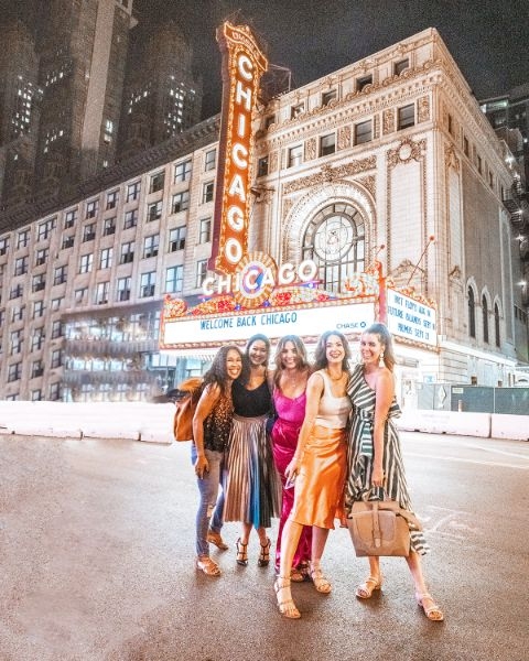 Group of stylish women standing outside the Chicago theater at night