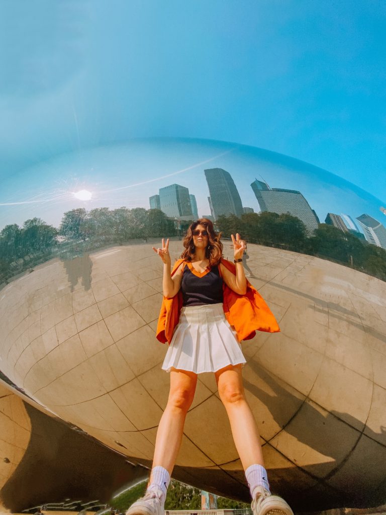 Girl standing in front of Chicago's Bean in Milllennium Park. The bean is a MUST for any chicago itinerary